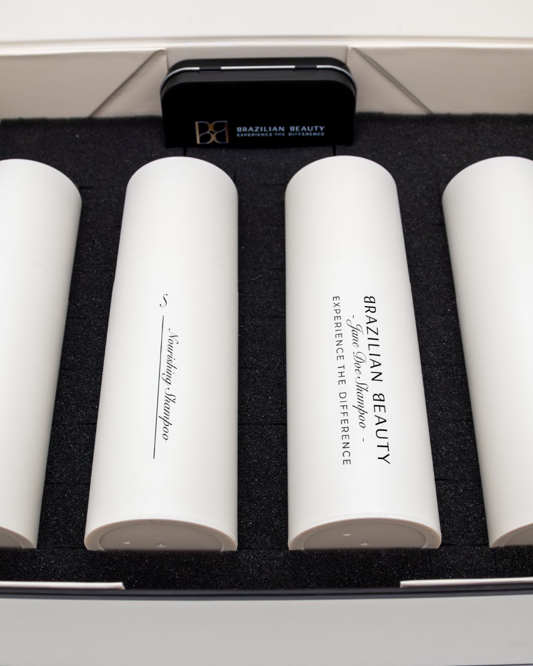 Set of white cylindrical containers with 'Brazilian Beauty' branding on a black foam.