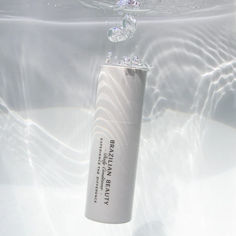 Brazilian Beauty Daily Conditioner bottle in a body of water with nice sunlight reflecting around it 